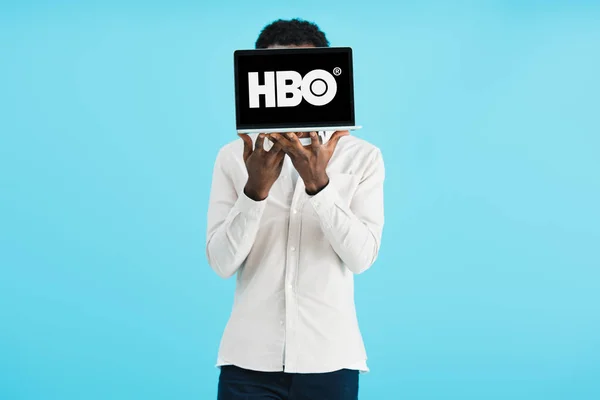 KYIV, UCRANIA - 17 DE MAYO DE 2019: hombre afroamericano mostrando portátil con el sitio web de HBO, aislado en azul - foto de stock