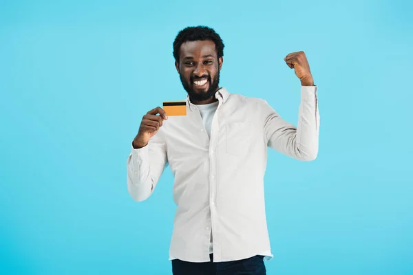 Excited african american man showing credit card isolated on blue — Stock Photo