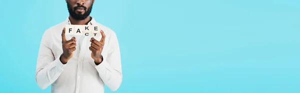 Abgeschnittene Ansicht eines afrikanisch-amerikanischen Mannes, der Buchstabenwürfel mit Tatsachenwort hält, isoliert auf blau — Stockfoto