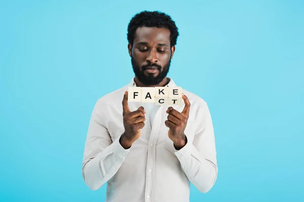 Jovem afro-americano segurando cubos alfabeto com palavra fato, isolado em azul — Fotografia de Stock