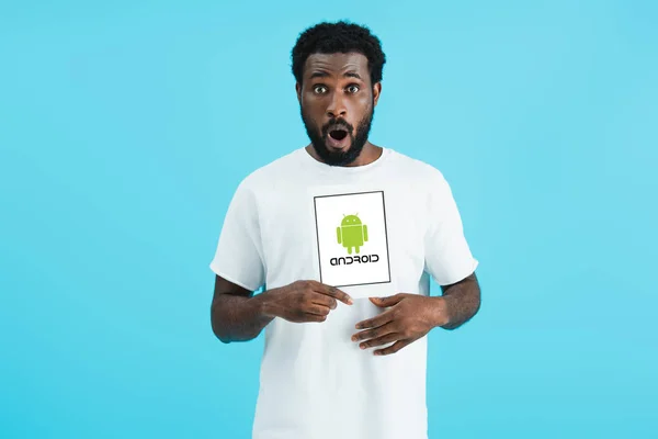 KYIV, UKRAINE - MAY 17, 2019: shocked african american man showing digital tablet with android app, isolated on blue — Stock Photo