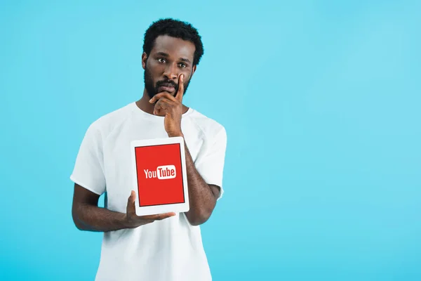 KYIV, UKRAINE - MAIO 17, 2019: homem afro-americano atencioso mostrando tablet digital com aplicativo youtube, isolado em azul — Fotografia de Stock