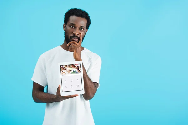 KYIV, UKRAINE - MAY 17, 2019: thoughtful african american man showing digital tablet with foursquare app, isolated on blue — Stock Photo