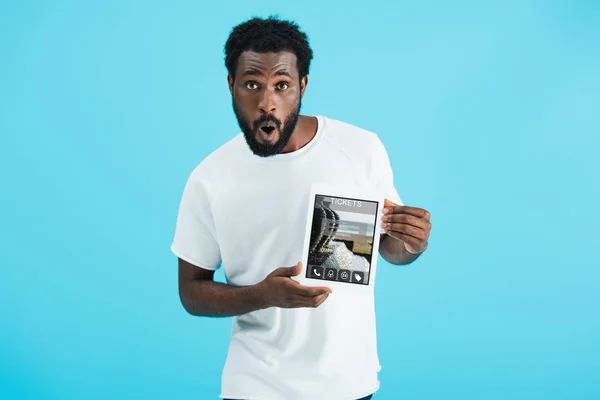 Shocked african american man showing digital tablet with tickets app, isolated on blue — Stock Photo