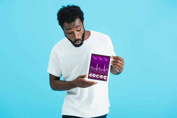 Shocked african american man showing digital tablet with health app, isolated on blue — Stock Photo