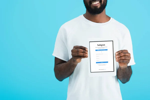 KYIV, UCRANIA - 17 DE MAYO DE 2019: vista recortada del hombre afroamericano mostrando tableta digital con aplicación instagram, aislado en azul — Stock Photo