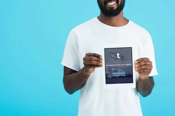 KYIV, UKRAINE - MAY 17, 2019: cropped view of african american man showing digital tablet with tumblr app, isolated on blue — Stock Photo