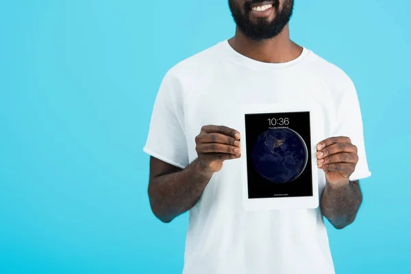 KYIV, UCRANIA - 17 DE MAYO DE 2019: vista recortada del hombre afroamericano mostrando tableta digital, aislado en azul - foto de stock