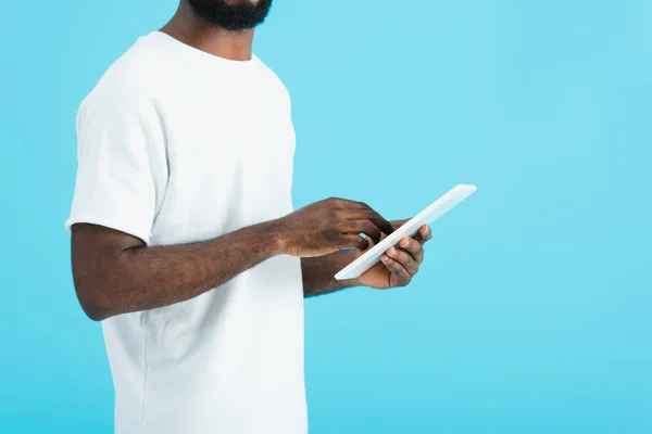 Vista recortada del hombre afroamericano en camiseta blanca usando tableta digital aislada en azul - foto de stock