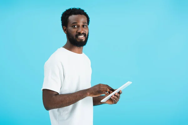 Усміхнений афроамериканський чоловік використовує цифровий планшет ізольовано на синьому — стокове фото