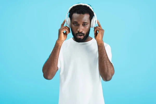 Concentrated african american man listening music with headphones, isolated on blue — Stock Photo