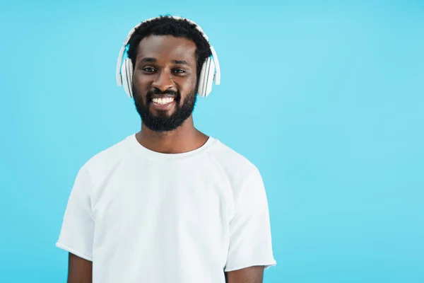 Homem americano africano alegre ouvindo música com fones de ouvido, isolado em azul — Fotografia de Stock