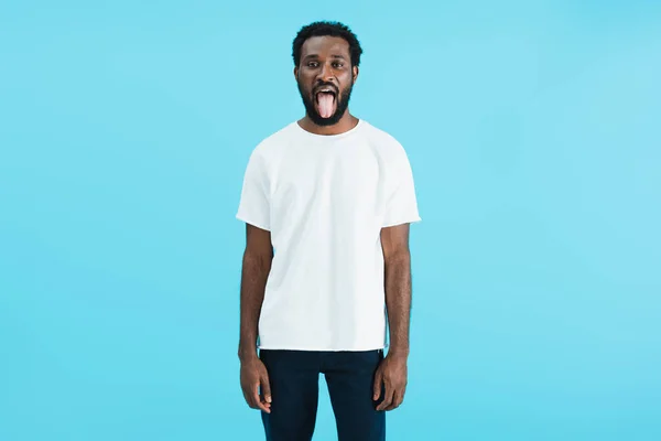 Handsome african american man sticking tongue out isolated on blue — Stock Photo