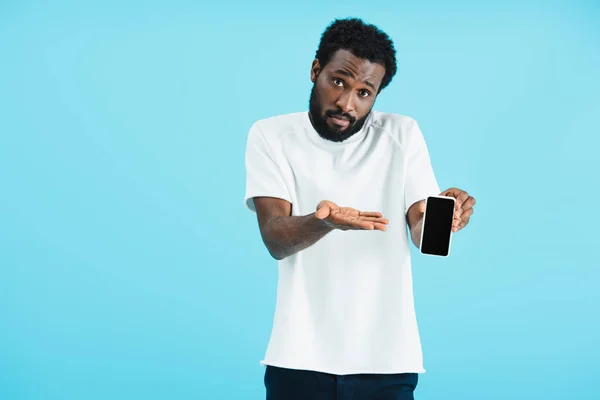 Homme afro-américain frustré montrant smartphone avec écran blanc, isolé sur bleu — Photo de stock