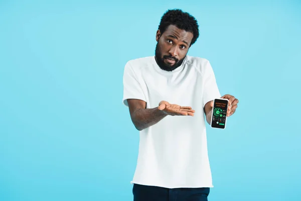 Frustrado homem afro-americano mostrando smartphone com aplicativo de análise de marketing, isolado em azul — Fotografia de Stock