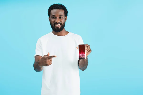 Усміхнений афроамериканський чоловік вказує на смартфон з торговими курсами, ізольований на синьому — стокове фото