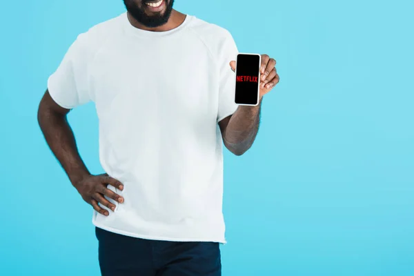 KYIV, UKRAINE - 17 MAI 2019 : vue recadrée de l'homme afro-américain montrant smartphone avec application netflix, isolé sur bleu — Photo de stock