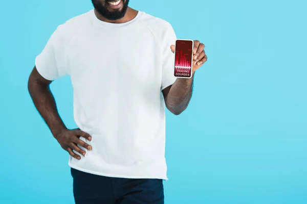 Abgeschnittene Ansicht eines afrikanisch-amerikanischen Mannes, der ein Smartphone mit Handelskursen zeigt, isoliert auf blauem Grund — Stockfoto