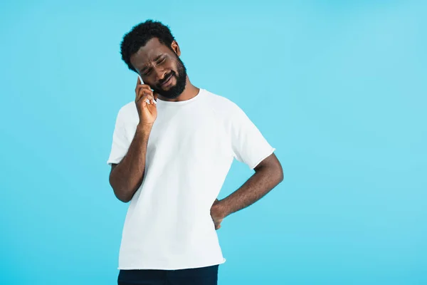 Засмучений афроамериканець людина розмовляє на смартфоні, ізольований по синьому — стокове фото