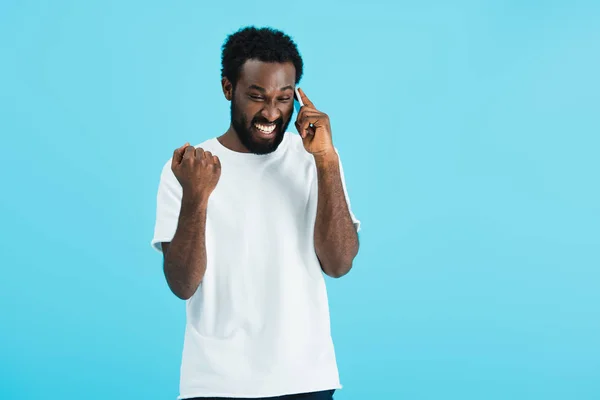 Hombre afroamericano emocionado hablando en el teléfono inteligente, aislado en azul - foto de stock