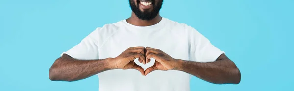 Vista recortada de hombre americano africano alegre que muestra el signo del corazón aislado en azul - foto de stock