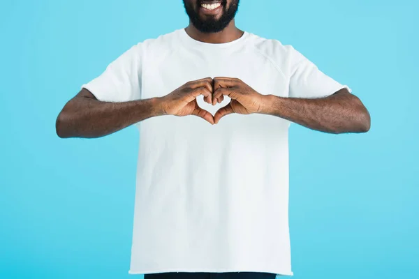 Vista cortada de homem americano africano sorridente mostrando sinal de coração isolado no azul — Fotografia de Stock