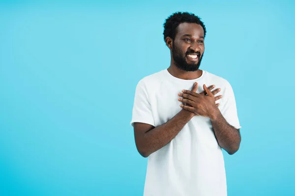 Cheerful african american man holding hands on heart isolated on blue — Stock Photo