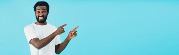 Усміхнений афроамериканський чоловік вказує ізольовано на синій — стокове фото