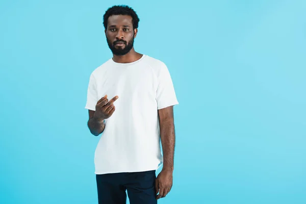 Serious african american man in white t-shirt showing middle finger isolated on blue — Stock Photo