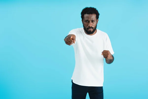 Homme afro-américain agressif en t-shirt blanc pointant vers vous isolé sur bleu — Photo de stock