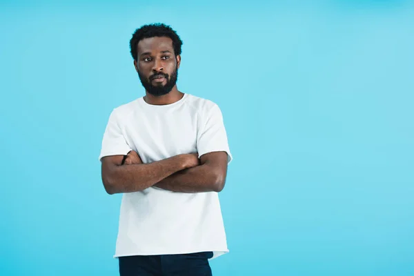 Pensive african american man in white t-shirt with crossed arms isolated on blue — Stock Photo