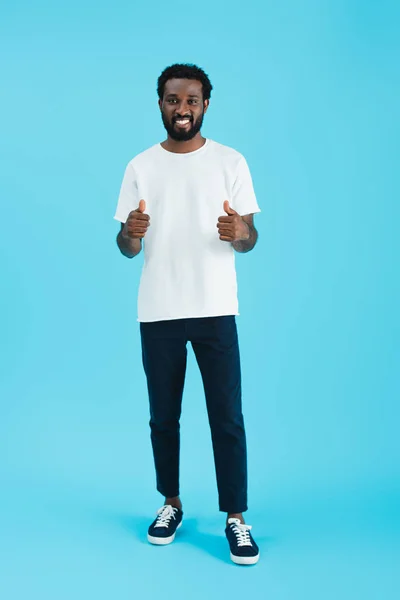 Homme afro-américain souriant montrant pouces isolés sur bleu — Photo de stock