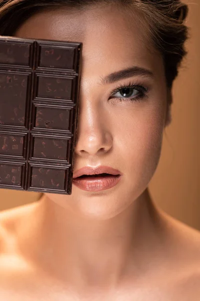 Retrato de bela jovem mulher nua segurando barra de chocolate isolado no bege — Fotografia de Stock