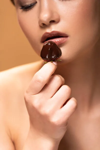 Young naked woman looking at strawberry in melted chocolate isolated on beige — Stock Photo