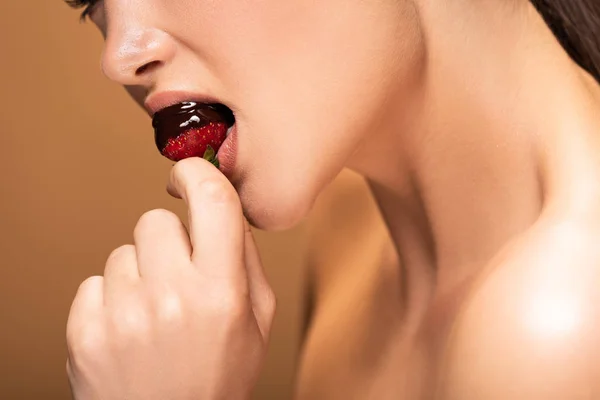 Cropped view of beautiful naked woman eating strawberry in melted chocolate isolated on beige — Stock Photo