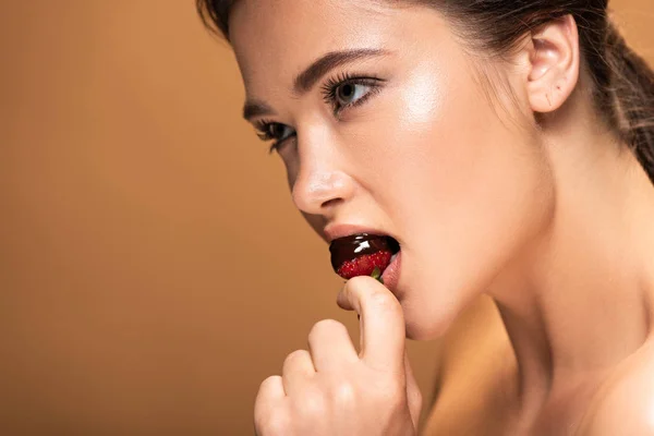 Beautiful naked woman eating strawberry in melted chocolate isolated on beige — Stock Photo