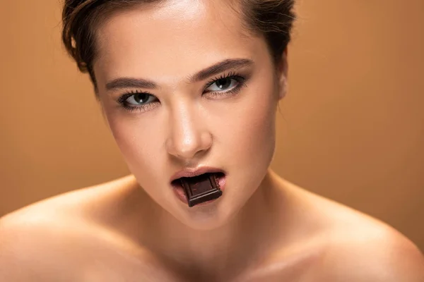 Attraente donna nuda in possesso di pezzo di cioccolato isolato su beige — Foto stock