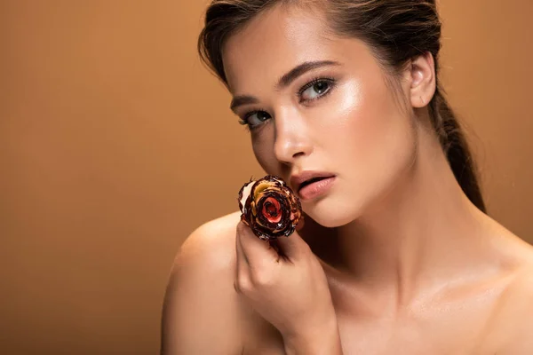 Naked woman holding rose covered with melted chocolate isolated on beige — Stock Photo