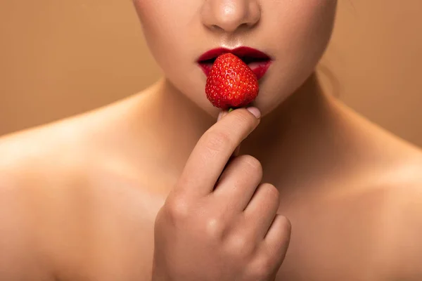 Visão parcial de mulher bonita nua segurando morango perto de lábios isolados em bege — Fotografia de Stock