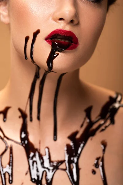 Частковий вид на голу жінку з червоними губами та шоколадними розливами на шкірі ізольовані на бежевому — стокове фото