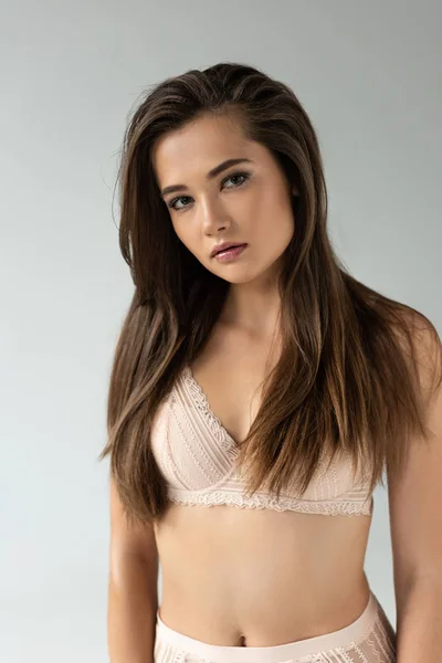 Hermosa joven en lencería beige aislada en gris - foto de stock