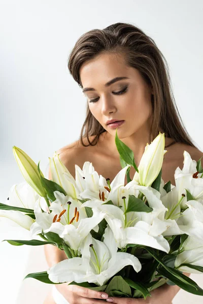 Нежная молодая женщина держит лилии с закрытыми глазами изолированы на белом — стоковое фото