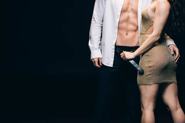 Teilansicht der sexy brünetten Frau entkleidet Freund mit muskulösem Oberkörper isoliert auf schwarz mit Kopierraum — Stockfoto