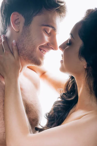 Joven pareja desnuda con los ojos cerrados abrazando y sonriendo aislado en blanco - foto de stock