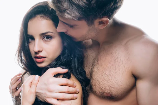 Mujer joven desnuda mirando a la cámara mientras se abraza con el novio aislado en blanco - foto de stock