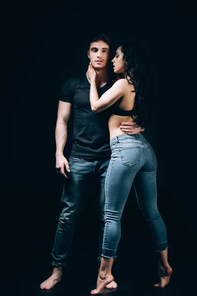 Босоногая пара в джинсах, стоящая в изоляции на черном — стоковое фото