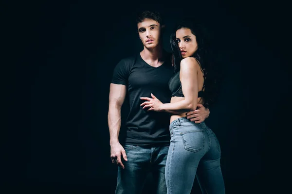 Junges Paar in Jeans umarmt sich isoliert auf schwarz — Stockfoto