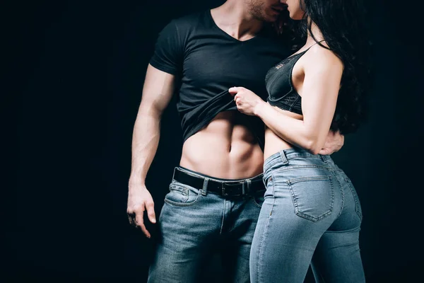 Cropped view of couple in denim kissing and undressing isolated on black — Stock Photo