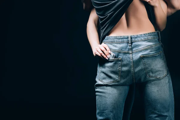 Rückansicht einer Frau, die Mann in Jeans anfasst und Kondom aus Tasche nimmt, isoliert auf schwarz — Stockfoto