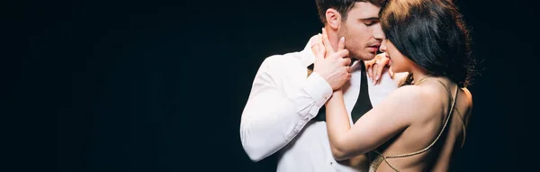 Colpo panoramico di giovane donna bruna baciare fidanzato isolato su nero — Stock Photo